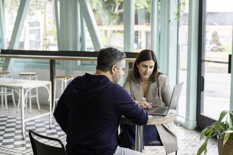 A man and woman collaborate at a table with a laptop, focusing on sales training and onboarding software solutions.